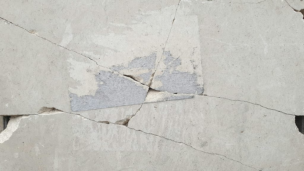 Close-up of cracked and damaged pavement representing a dangerous premise and common slip and fall hazard.