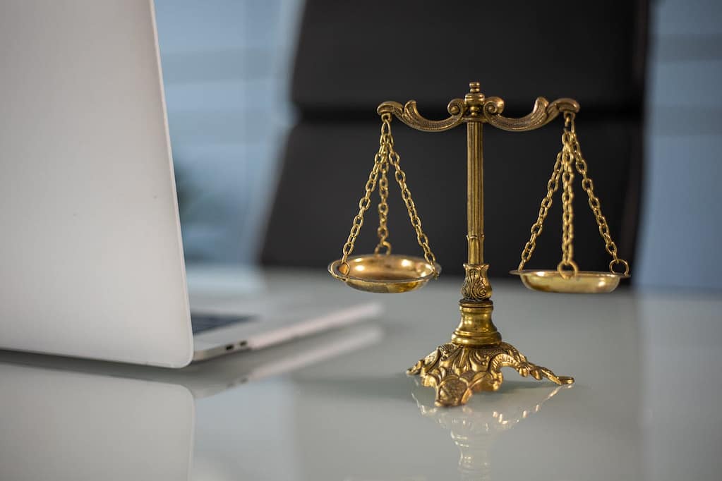 Scales of justice on desk beside laptop in California personal injury law office