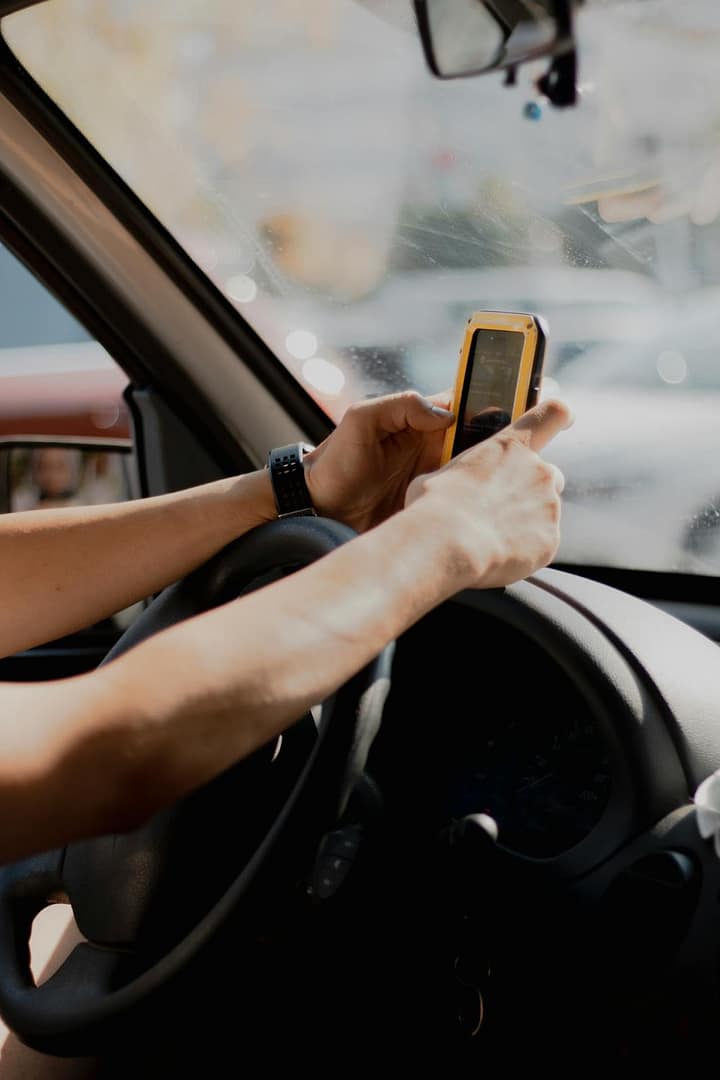 Driver taking a photo with a smartphone from inside the car—documenting the scene after a car accident in California.