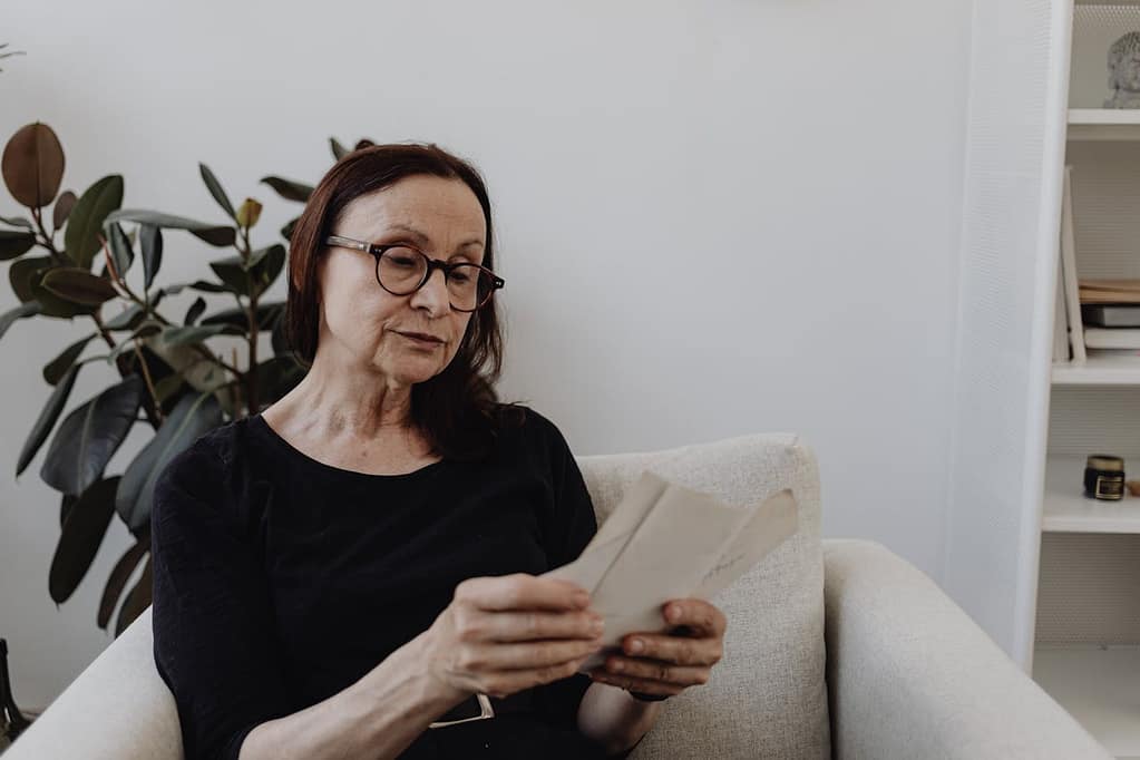Woman reading vehicle documents at home, gathering evidence for a lemon law claim after repeated warranty repairs failed to fix a defective vehicle in California