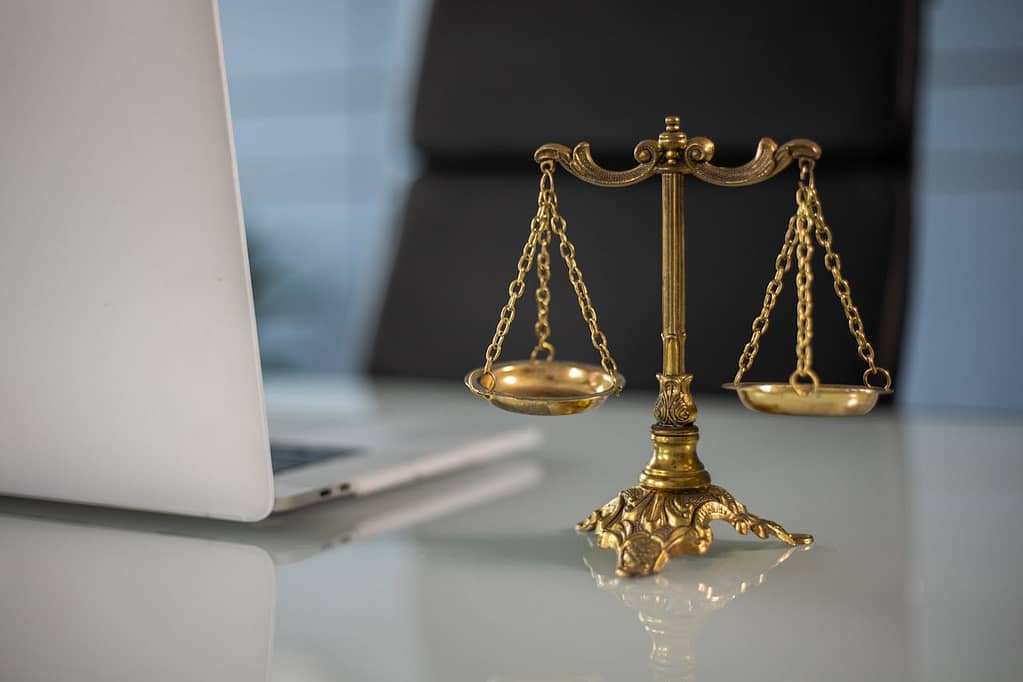 Scales of justice on desk beside laptop in California personal injury law office

