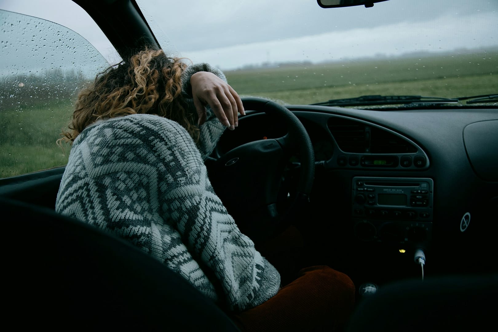 California car accident victim leaning on steering wheel, overwhelmed with emotion feelings after a car accident