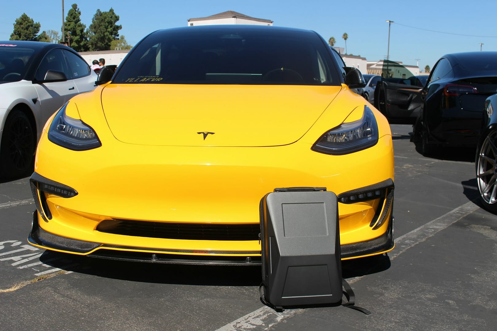 Bright yellow Tesla Model 3 parked with a case in front, symbolizing EV ownership frustrations and lemon law concerns in California.