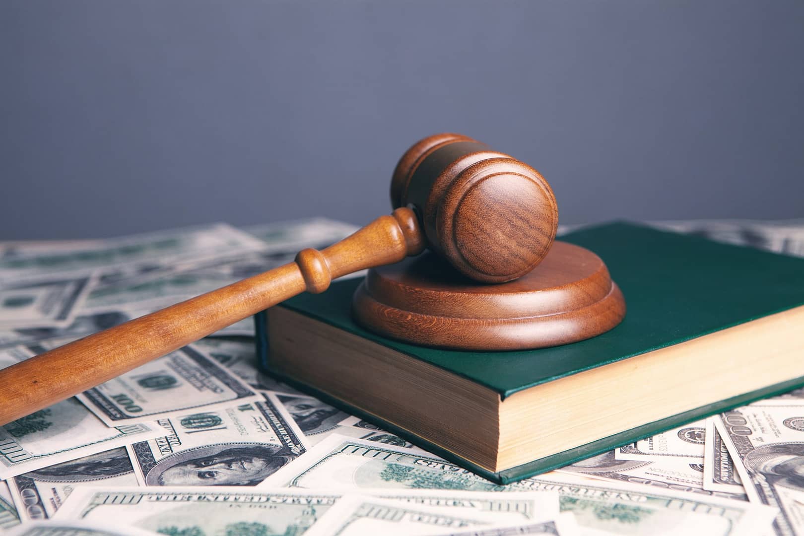 A wooden gavel resting on a book and dollar bills, symbolizing compensation in personal injury cases