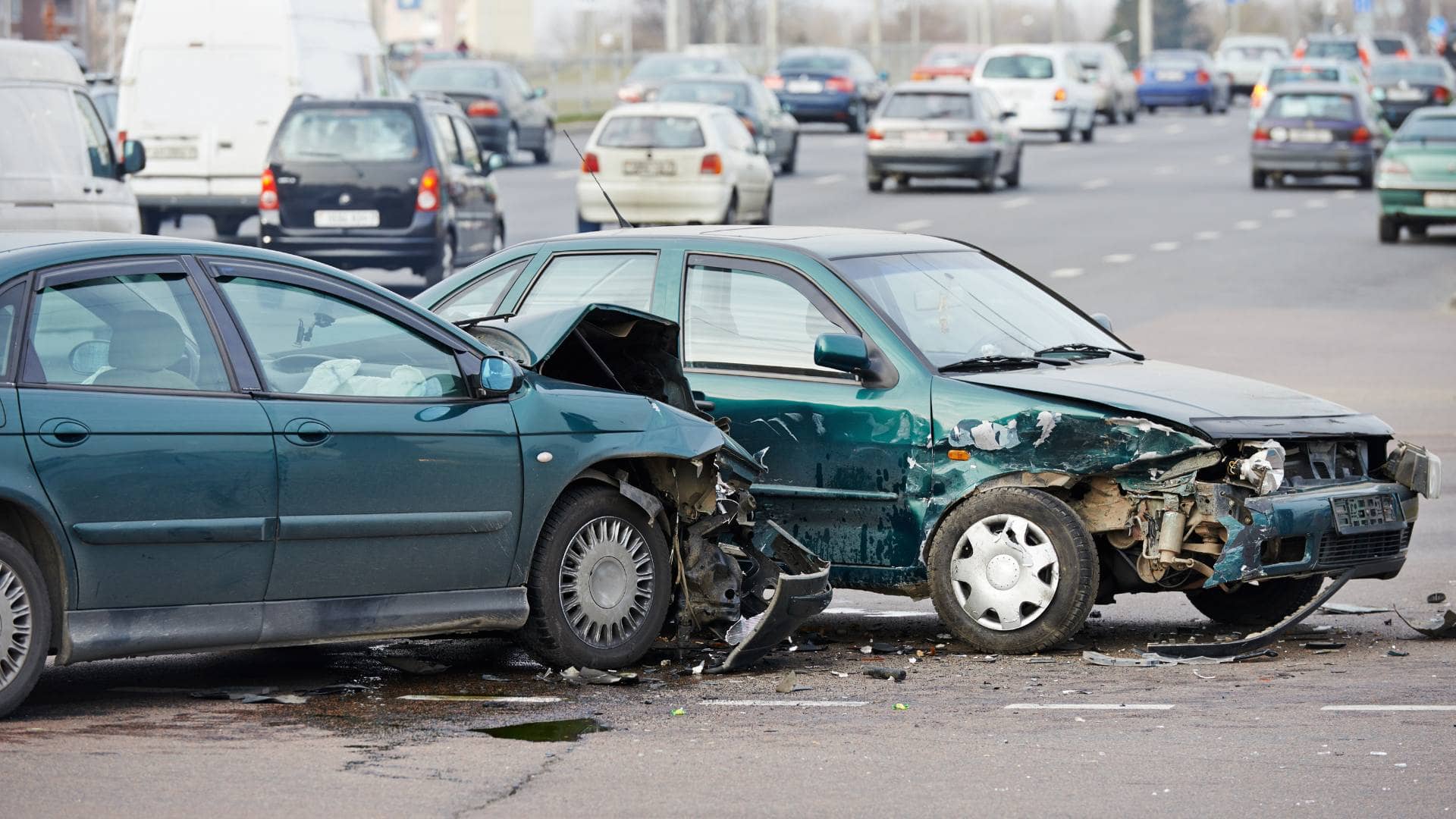 Two cars show front and side damage after a collision on a busy multi-lane road; other vehicles are visible in the background, highlighting the aftermath where a car accident lawyer might be needed.