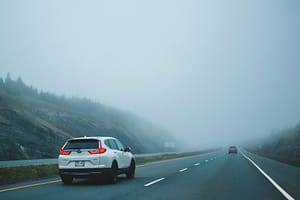 A Car driving cautiously on a foggy road