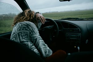 California car accident victim leaning on steering wheel, overwhelmed with emotion feelings after a car accident